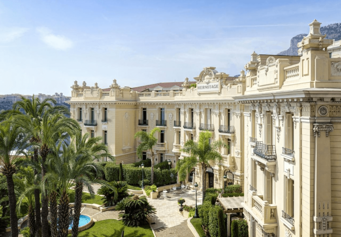"Majestic hotel in Monaco, surrounded by a beautifully landscaped garden full of exotic plants and flowers."