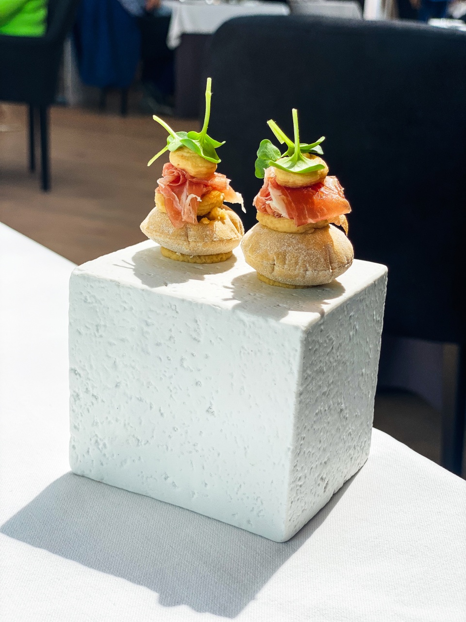 Een prachtige presentatie van verfijnde hapjes op een elegante schaal in restaurant De Bakermat, waarbij elk hapje zorgvuldig is bereid om een uitbarsting van smaak en textuur te bieden."
