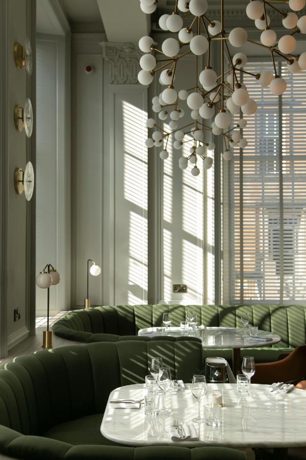 Een uitnodigende afbeelding van de lobby van het Kimpton Blythswood Square Hotel, met een elegante mix van moderne designelementen en historische weelde, met pluche meubilair en warme sfeerverlichting.