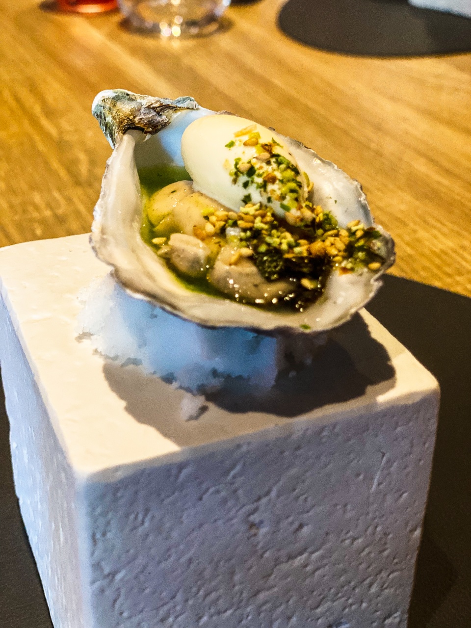 Verfijnde gillardeau oester op een bedje van ijs, gepresenteerd op een stijlvol bord, kenmerkend voor de culinaire innovatie bij Restaurant Zappaz in Leuven
