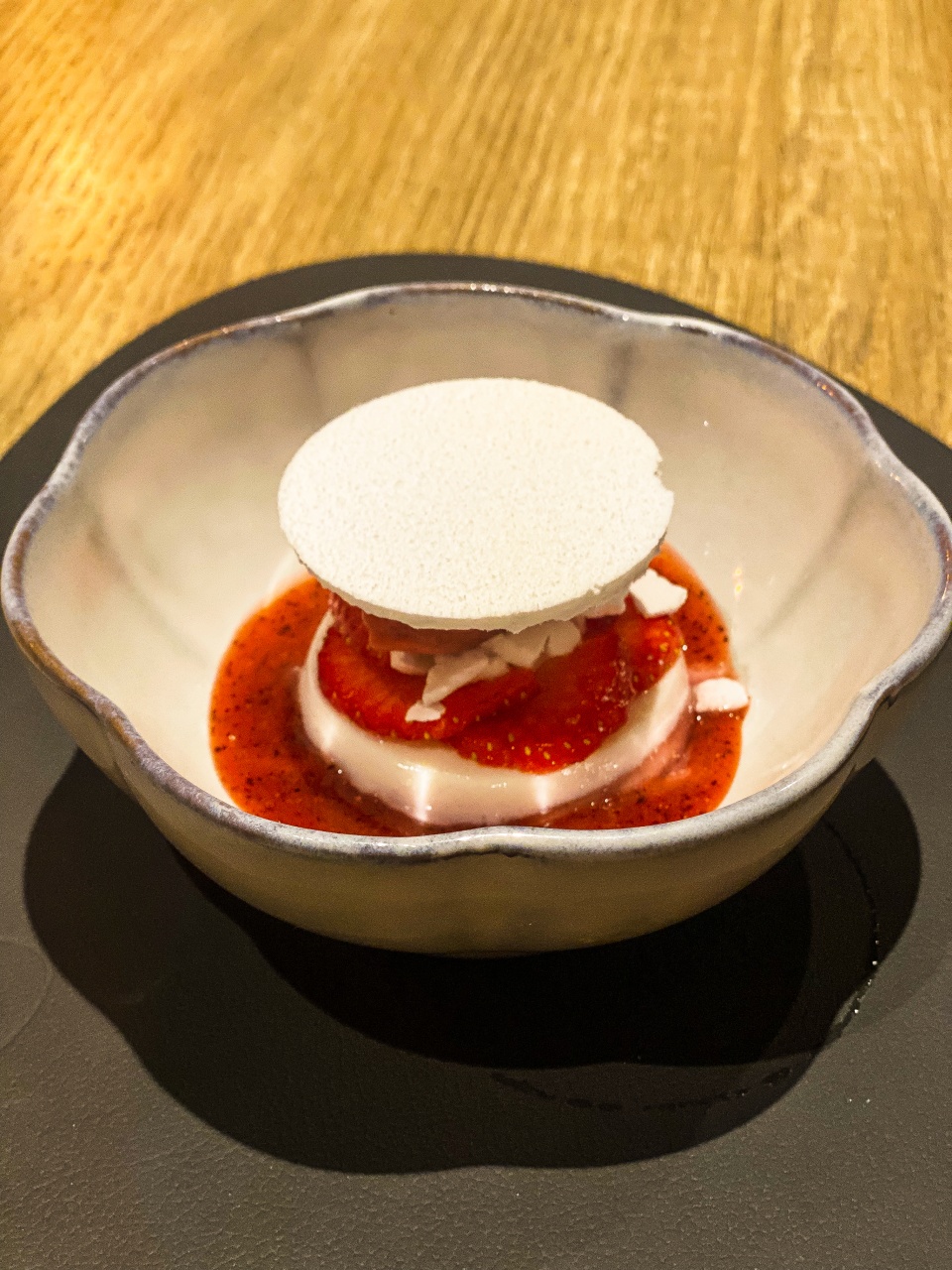 Een verleidelijk dessert bestaande uit sappige aardbeien harmonieus gecombineerd met frisse shiso, kunstig opgemaakt op een verfijnd bord, dat de zoete innovatie van Restaurant Zappaz in Leuven belichaamt
