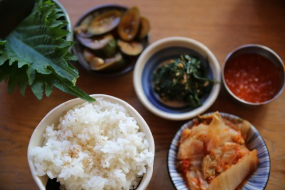 Assortiment van authentieke Koreaanse gerechten, inclusief kimchi, gegrilde makreel, en stir-fried octopus, smaakvol gepresenteerd op uniek keramiek servies.