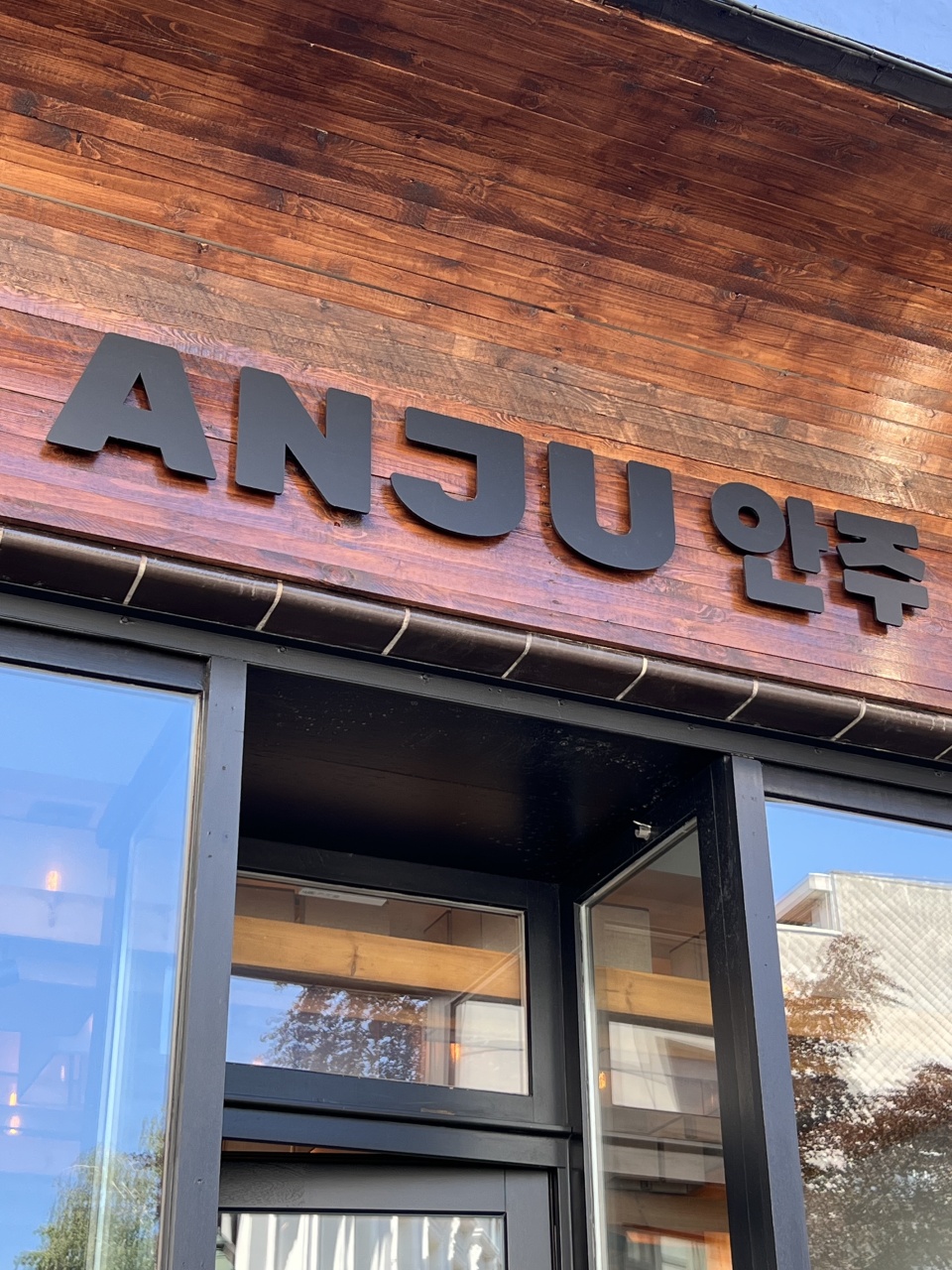 Exterieur van het Anju restaurant in Brussel, met kenmerkende rode krukjes op het straatterras en een uitnodigende, gezellige sfeer.