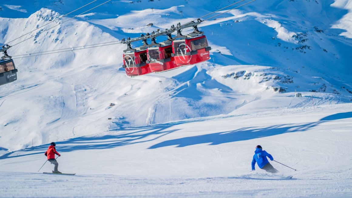 Large ski lift cabin transports skiers with a vast snowy landscape in the background