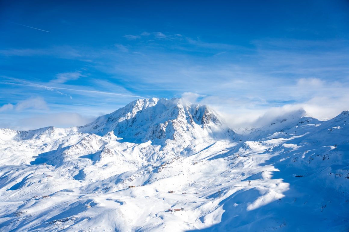 Panoramic view of a pristine snowy landscape with pine trees and rolling hills.