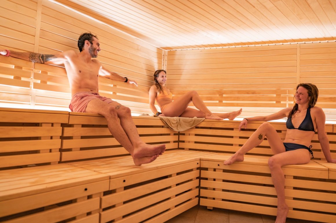 Alt text for 2 people in sauna: Two people relaxing in a wooden sauna surrounded by steam and heat.