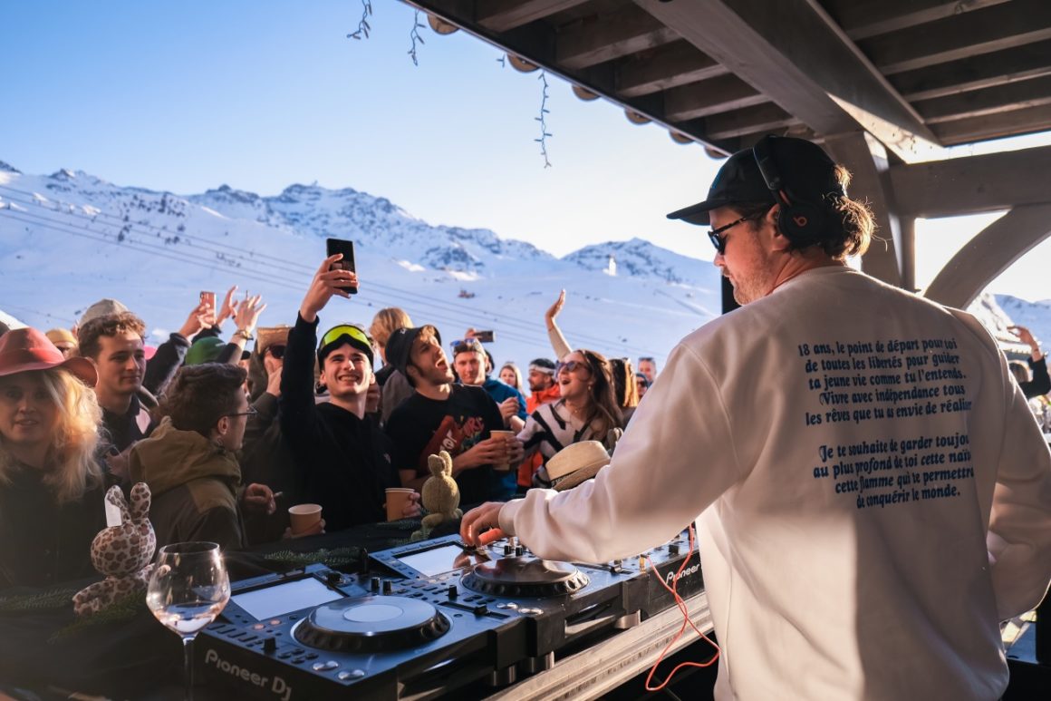 Feestende menigte danst in de sneeuw terwijl de DJ energieke muziek draait vanaf het podium.