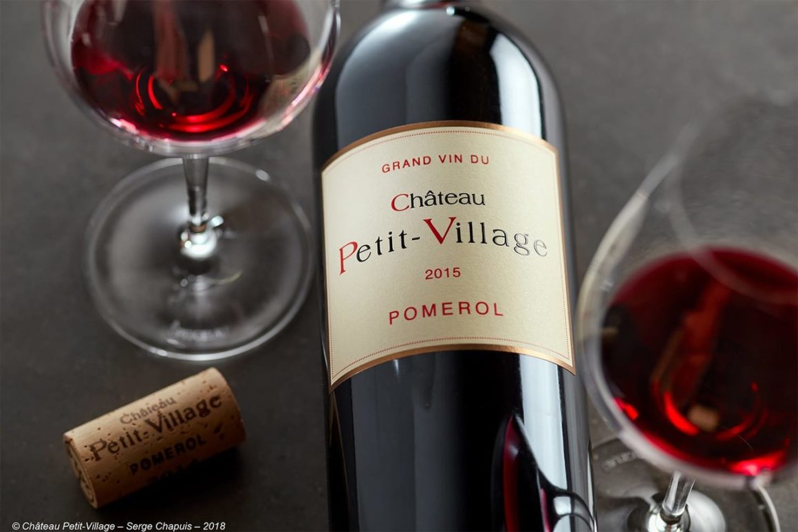 Fles wijn van Château Petit Village, millésime 2010, elegant uitgeschonken in een glas.