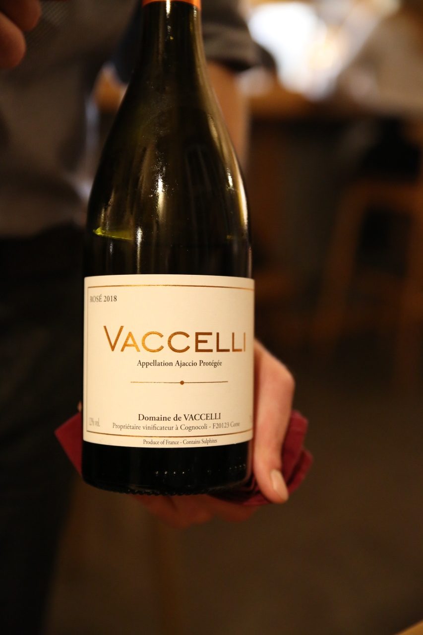 An elegant bottle of wine from the "Vaccelli" brand is prominently presented. The label is clearly visible, indicating a premium selection. The setting suggests a formal or special occasion.