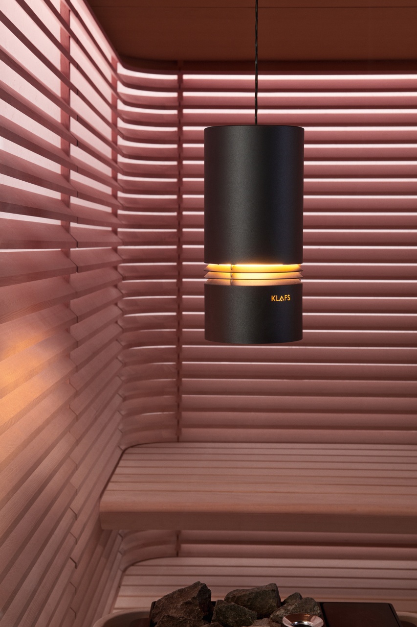 Het tweede beeld toont een detail van een sauna. De roze houten lambrisering en de eenvoudige accessoires creëren een kalmerende en ontspannende sfeer