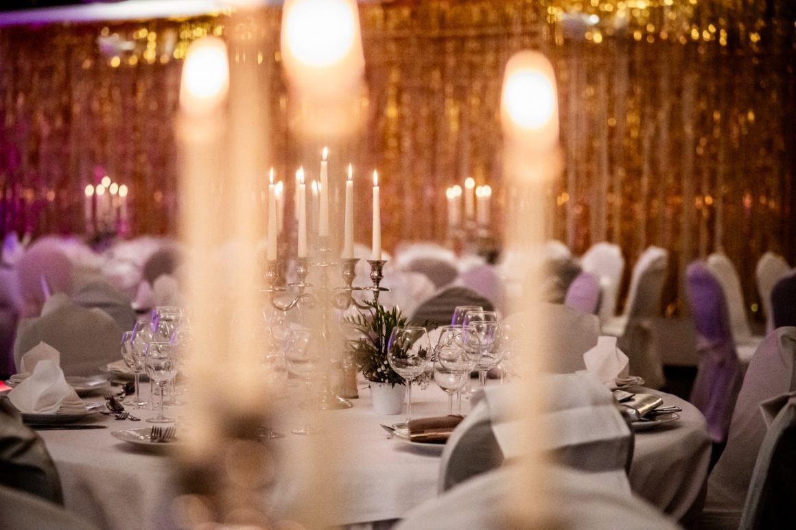 Een elegant gedekte tafel met kaarslicht en glinsterende decoratie voor een gala-evenement.