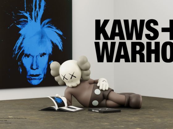 KAWS + Warhol tentoonstelling in UNIQLO UT, met een groot blauw zelfportret van Andy Warhol en een sculptuur van KAWS die op de grond ligt naast een open kunstboek, in een galerijachtige setting.