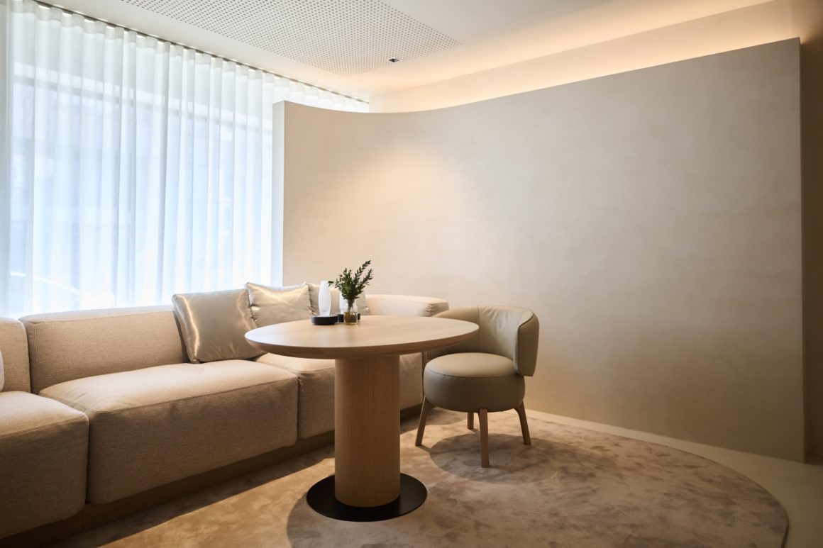 Intieme zithoek met ronde tafel en comfortabele sofa in zachte aardetinten, badend in natuurlijk licht – deel van het interieur van de Range Rover SV Bespoke Commissioning Studio.
