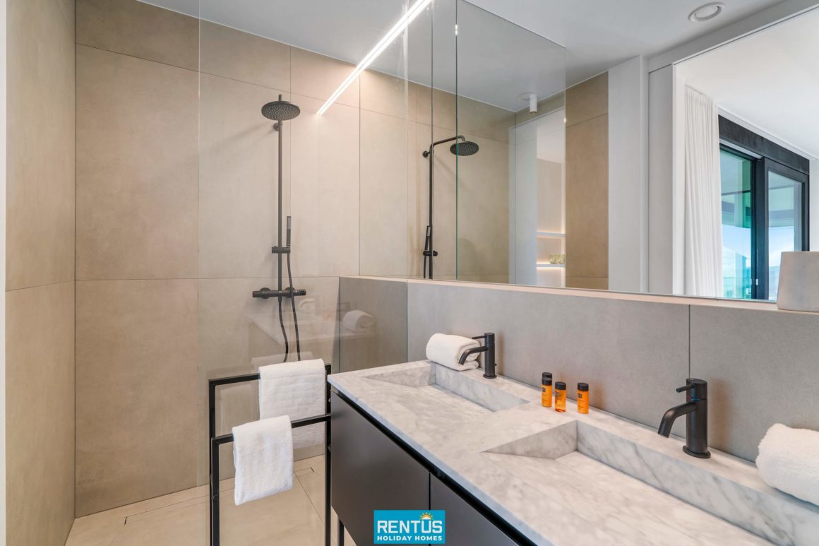 Moderne badkamer met dubbele marmeren wastafel en ruime inloopdouche.